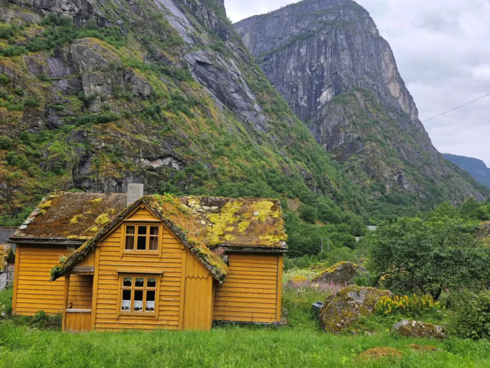 Gult gardshus under bratte fjell i Eidfjord